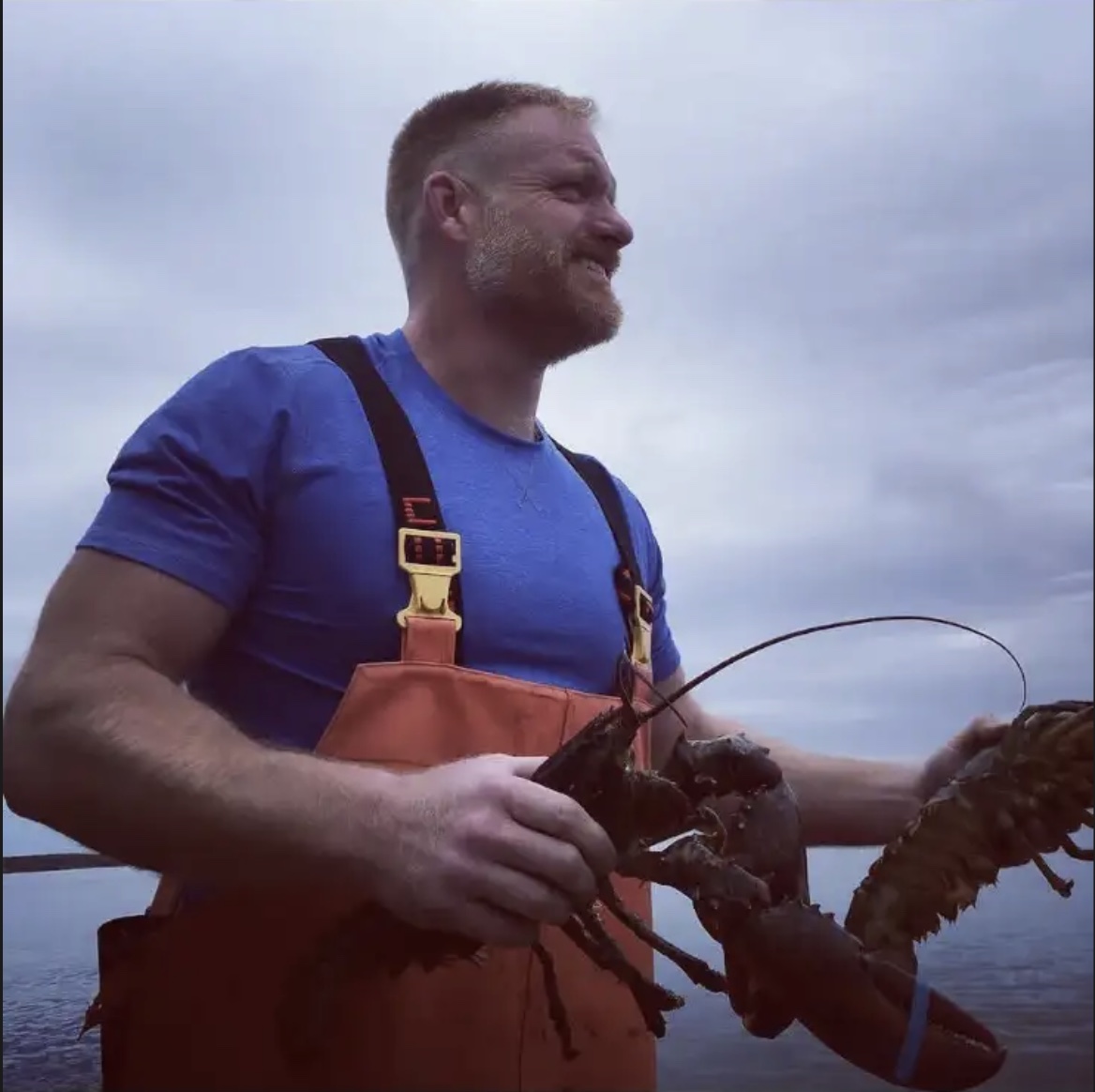 John Leavitt, Owner & CEO of Shucks, holding a freshly caught Maine lobster aboard a boat